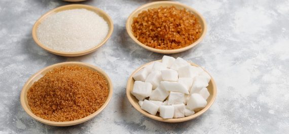 Various types of sugar, brown sugar and white on concrete backgr